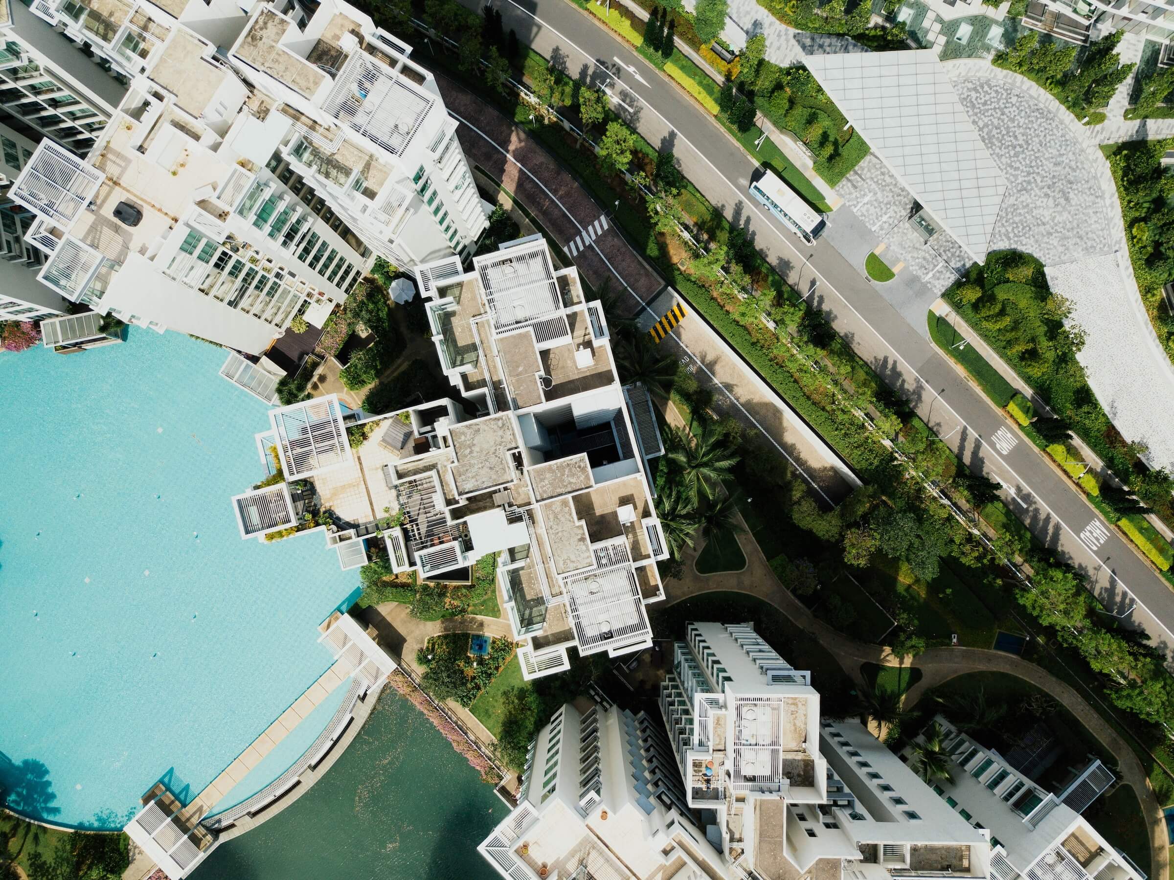 Aerial photo of white skyscrapers, greenery, and a light turquoise pool.